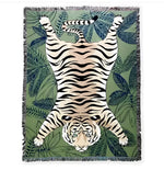 Tiger lying in green wild printed throw, flat lay — orange tiger on tropical leaf print, fringe