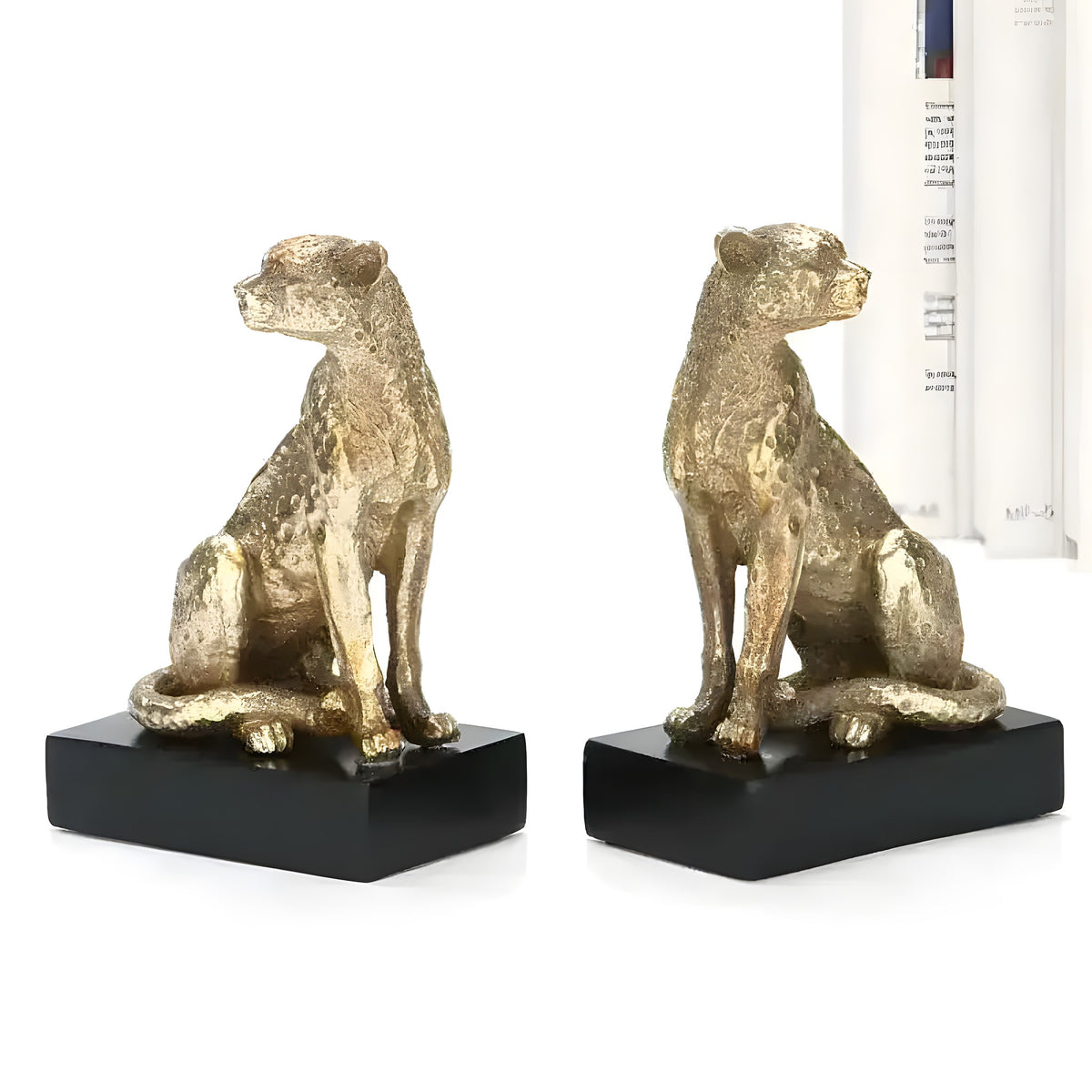 Two regal gold leopards bookends with textured detail on black bases, flanking books on white background