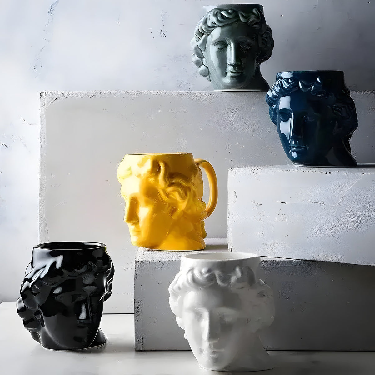 David's sculpture mugs in yellow, grey, navy, black and white on concrete pedestals