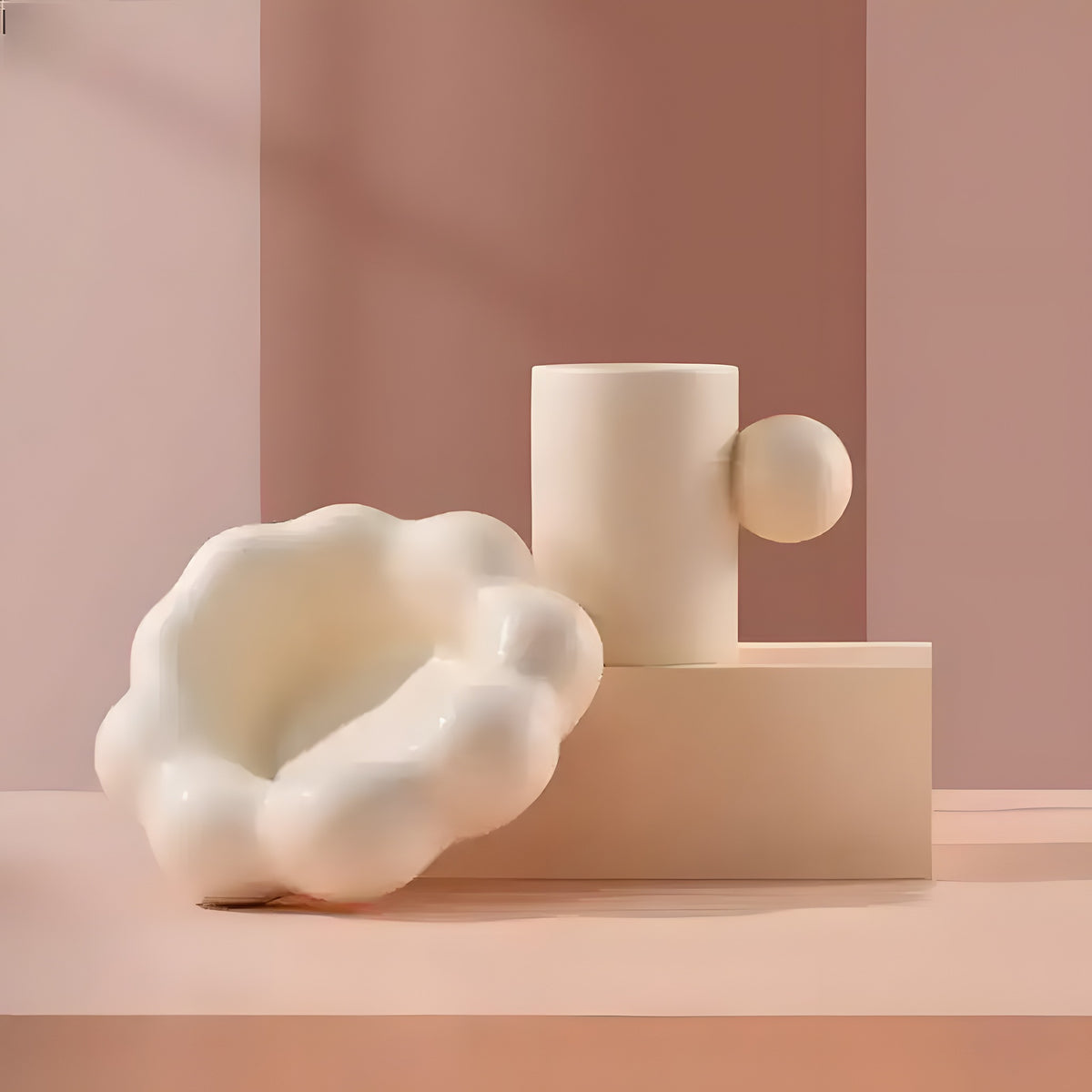Cream coffee mug with spherical handle on cloud-shaped saucer, pink geometric backdrop