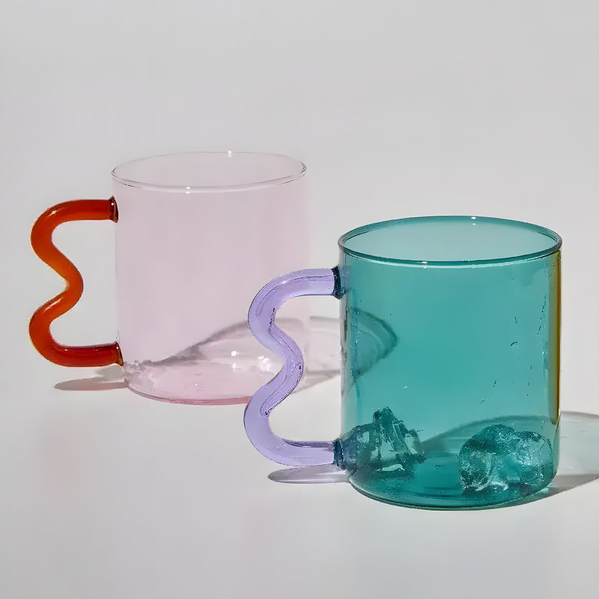 Pink and teal colored waved ear glasses with orange and purple wavy handles, front view on white background