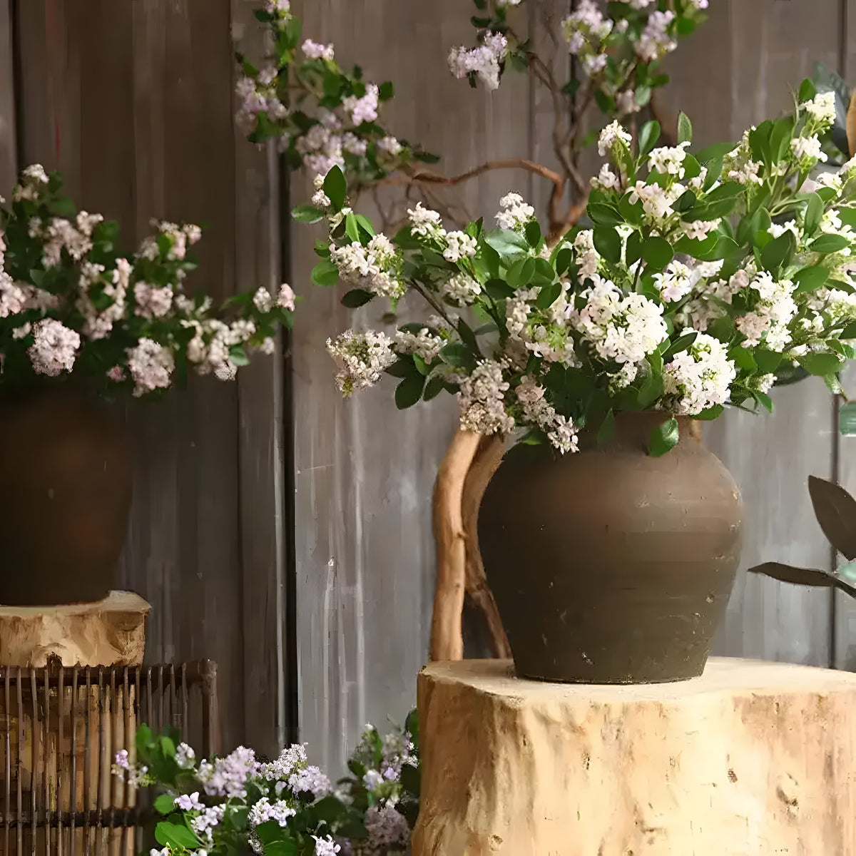 Silk thyme flower branch with white-lilac blossoms and green leaves, in a rustic clay pot on wooden stump