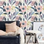 Vintage blush pink floral wallpaper in a living room, large blush poppy and blue botanical print on cream, behind dark sofa