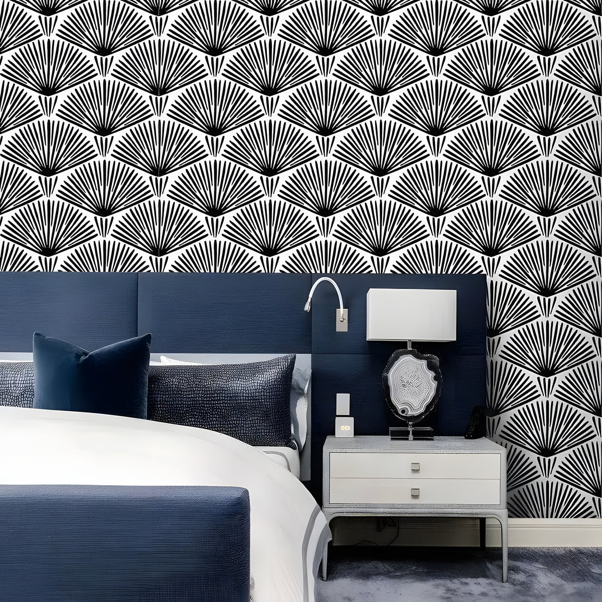 Black and white art deco fans wallpaper in elegant bedroom with navy upholstered headboard and lamp
