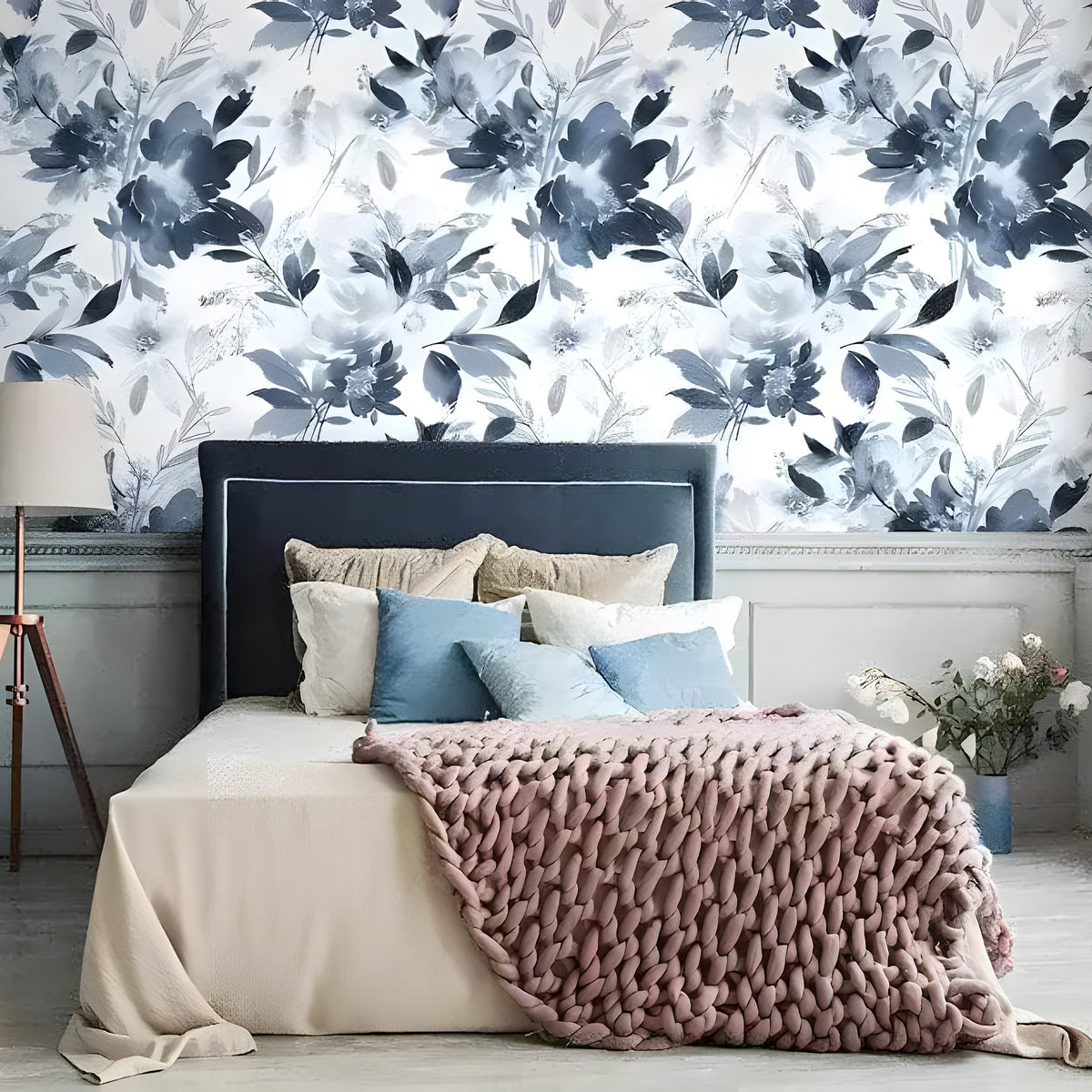 Blue watercolor abstract floral wallpaper with navy blooms and leaves, styled in a bedroom with layered neutral bedding