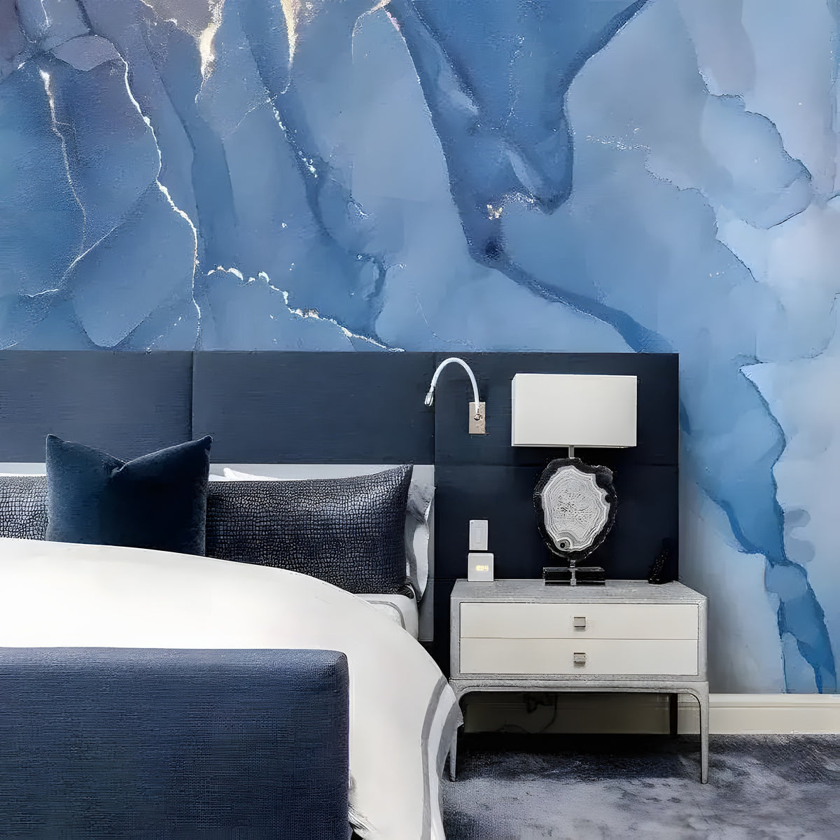 Abstract Blue Marble Mural above navy bed with dark pillows and silver nightstand, fluid blue ink with silver veins