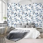Watercolor blue abstract wallpaper with scattered indigo and navy dot pattern, shown in modern bedroom