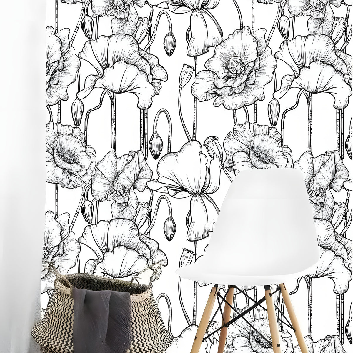 Black and white poppy floral wallpaper with fine line-drawn blooms and stems in a minimalist room with a white Eames chair and woven basket