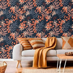 Botanical herbs and wildflowers watercolor wallpaper with rust ferns and orange berries on navy behind grey sofa with mustard cushions