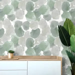 Abstract moss green watercolor wallpaper behind a white-wood sideboard with succulent and bird of paradise