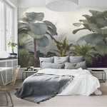 Misty tropical forest watercolor mural in bedroom with white bed, grey throw, gold wire chair and large window