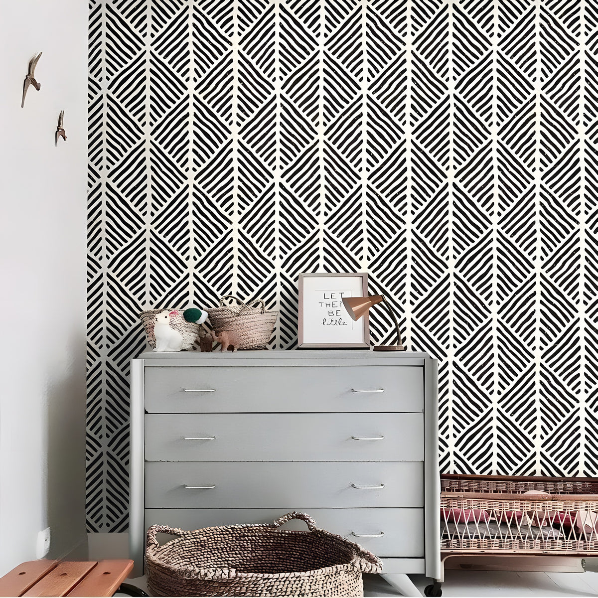 Alaia wallpaper in a nursery room setting - bold black-and-white geometric diamond stripe, gray dresser with wicker basket