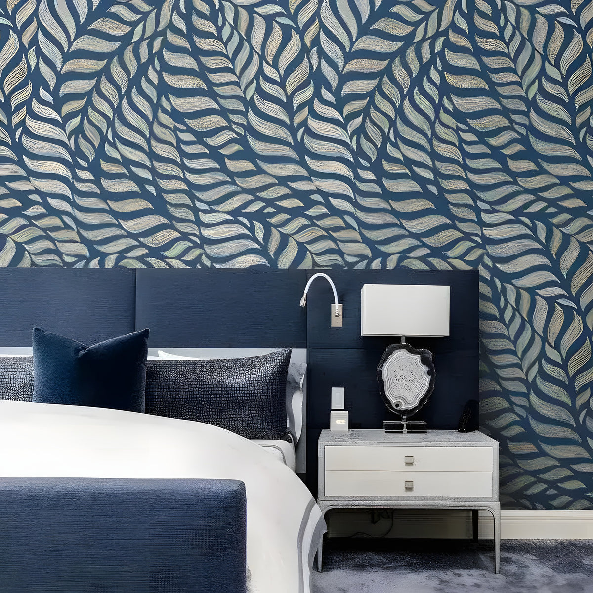 Abstract blue leaves mural as accent wall in navy bedroom with matching headboard and white nightstand