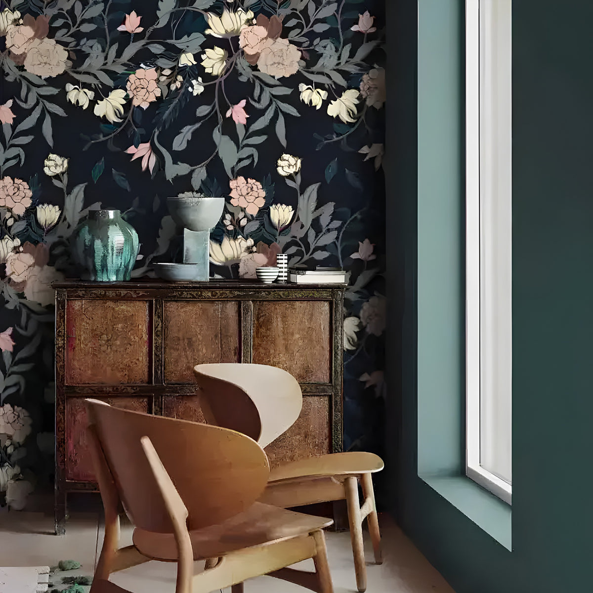 Vintage exotic flowers on dark wallpaper in a Scandi nook with a bentwood chair and antique cabinet with a teal vase