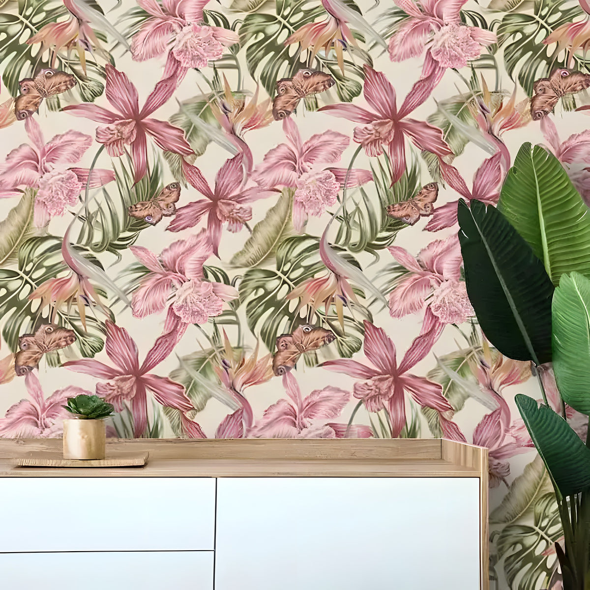 Vintage watercolored tropical monstera wallpaper in cream and dusty pink behind white oak dresser with bird of paradise plant