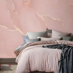 Pastel blush pink marble mural with sweeping white veins as a bedroom headboard wall behind pink bedding