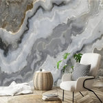 Faux agate marble abstract wallpaper mural with sweeping gray and cream swirls behind a cream bouclé chair
