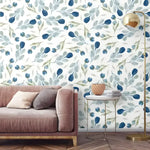 Minimalist blue floral wallpaper with ink-blue tulip buds on white behind a blush velvet sofa and gold ball floor lamp