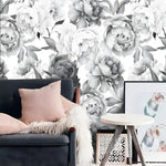 Romantic gray oversized peony wallpaper with a charcoal loveseat, pink cushion and wood tripod table