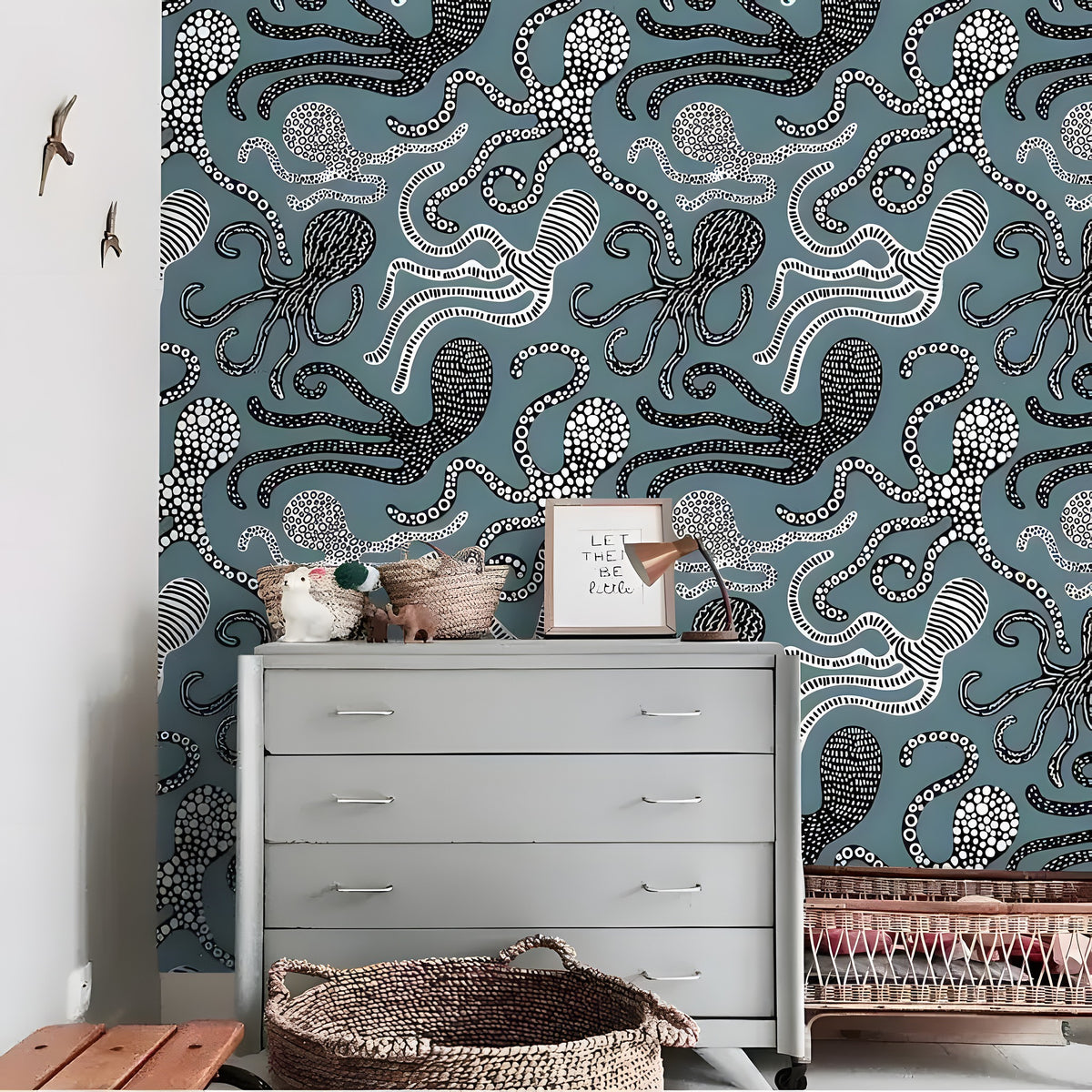 Grey chest of drawers with toy animals and wicker baskets; nautical swimming sea octopus wallpaper with dotted octopus on teal