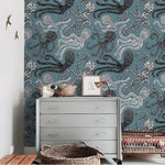 Grey chest of drawers with toy animals and wicker baskets; nautical swimming sea octopus wallpaper with dotted octopus on teal
