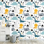 Cartoon dinosaur world wallpaper with teal, blue, and yellow dinos, volcanoes, and palms on white in a nursery