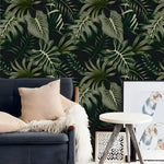 Lush green and black rainforest ferns wallpaper behind navy armchair with tan pillow and fur throw