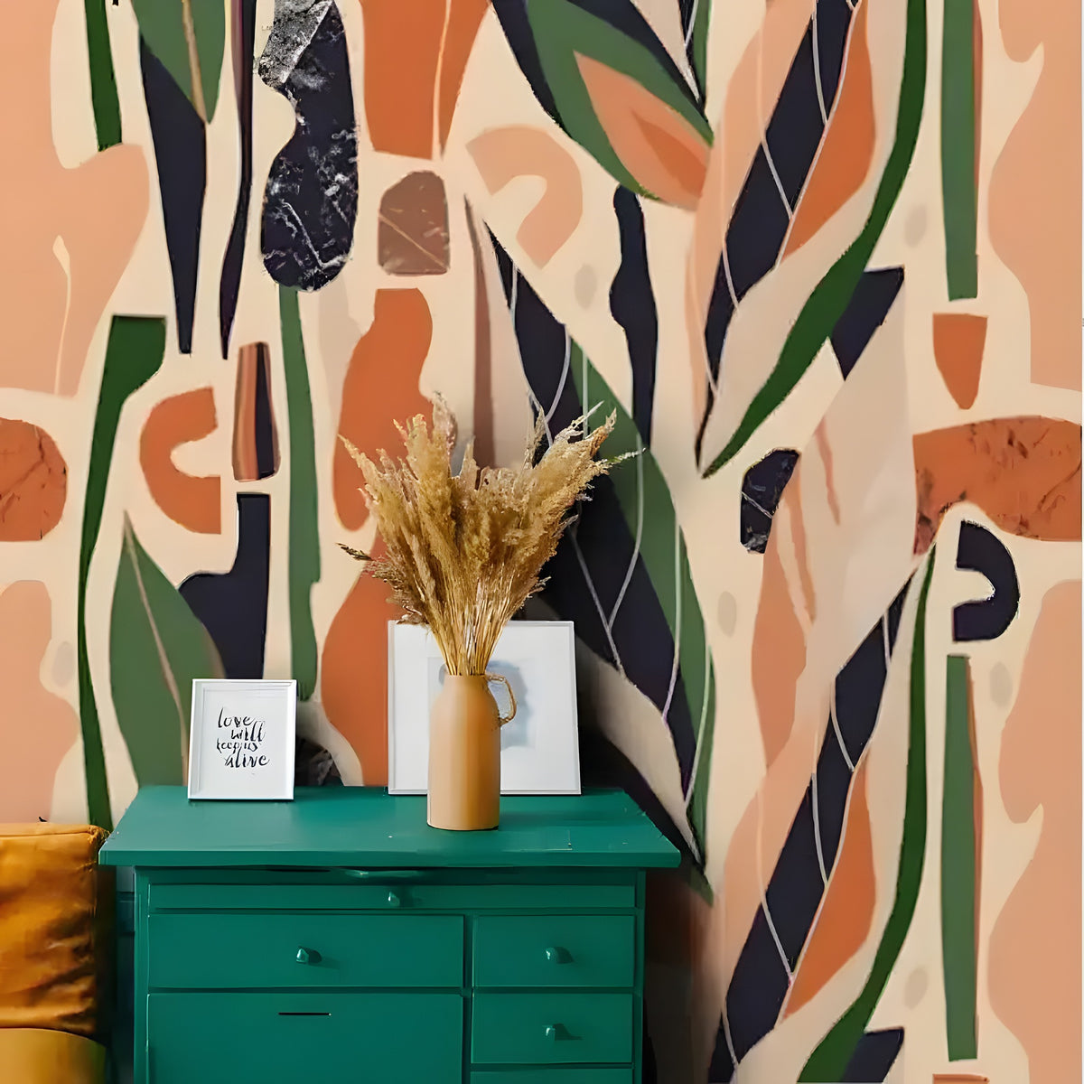 Terracotta abstract wallpaper with bold beige, orange, navy leaf shapes, styled over green dresser with dried floral arrangement