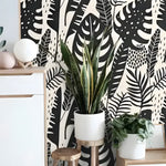 Black Illustrated Monstera wallpaper on cream, Scandi sideboard with tall snake plant in white pot