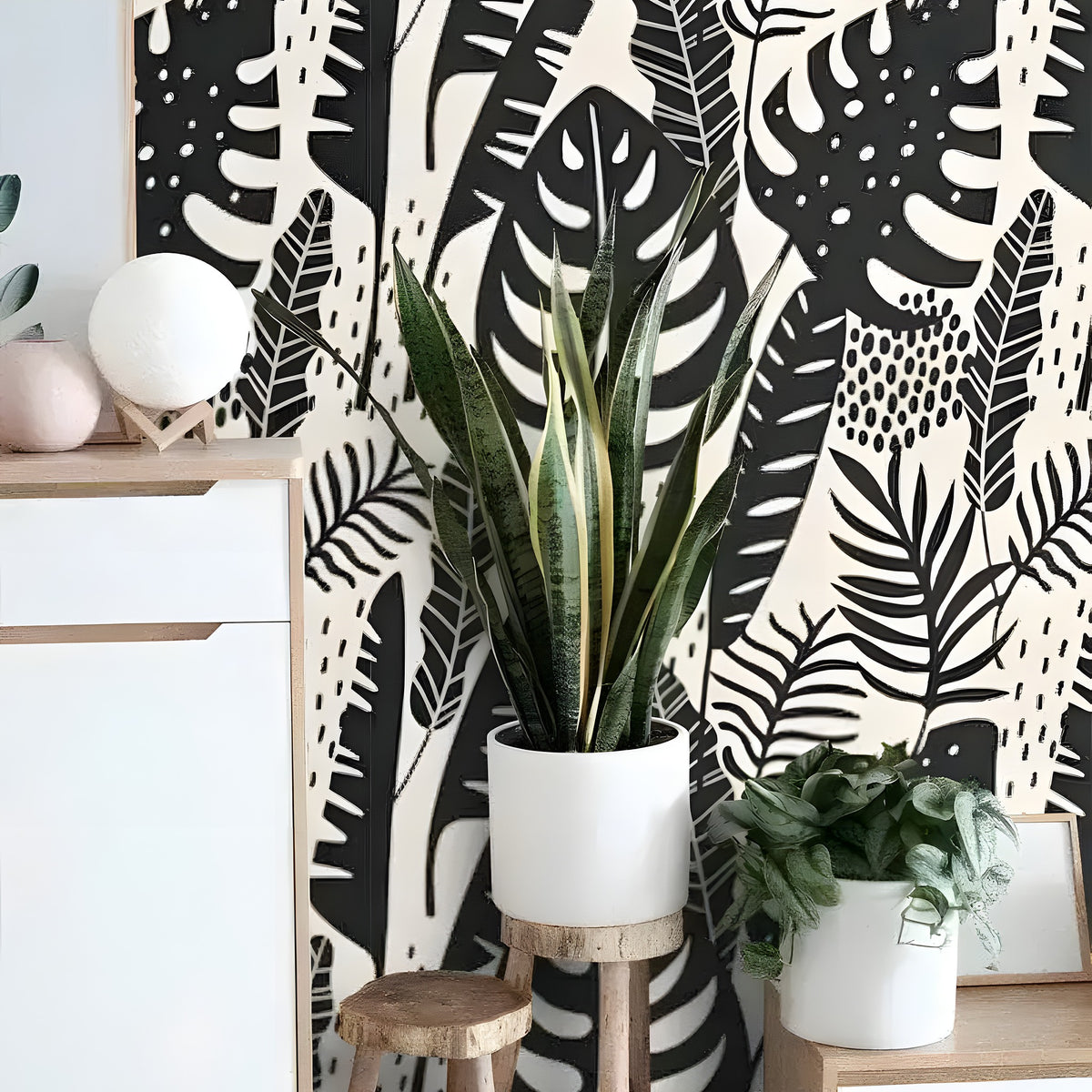 Black Illustrated Monstera wallpaper on cream, Scandi sideboard with tall snake plant in white pot
