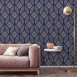 Navy background with large cream and white palm fronds wallpaper behind cream upholstered bed and gold circular nightstands
