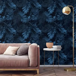 Large dark navy tropical foliage wallpaper in living room with pink velvet sofa and gold arc lamp
