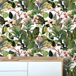 Green tropical leaves and flowers watercolor wallpaper with banana and calathea leaves and white orchids, behind a Scandi sideboard