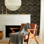 Gold and black art deco watercolor wallpaper in living room with marble fireplace, round mirror, armchair