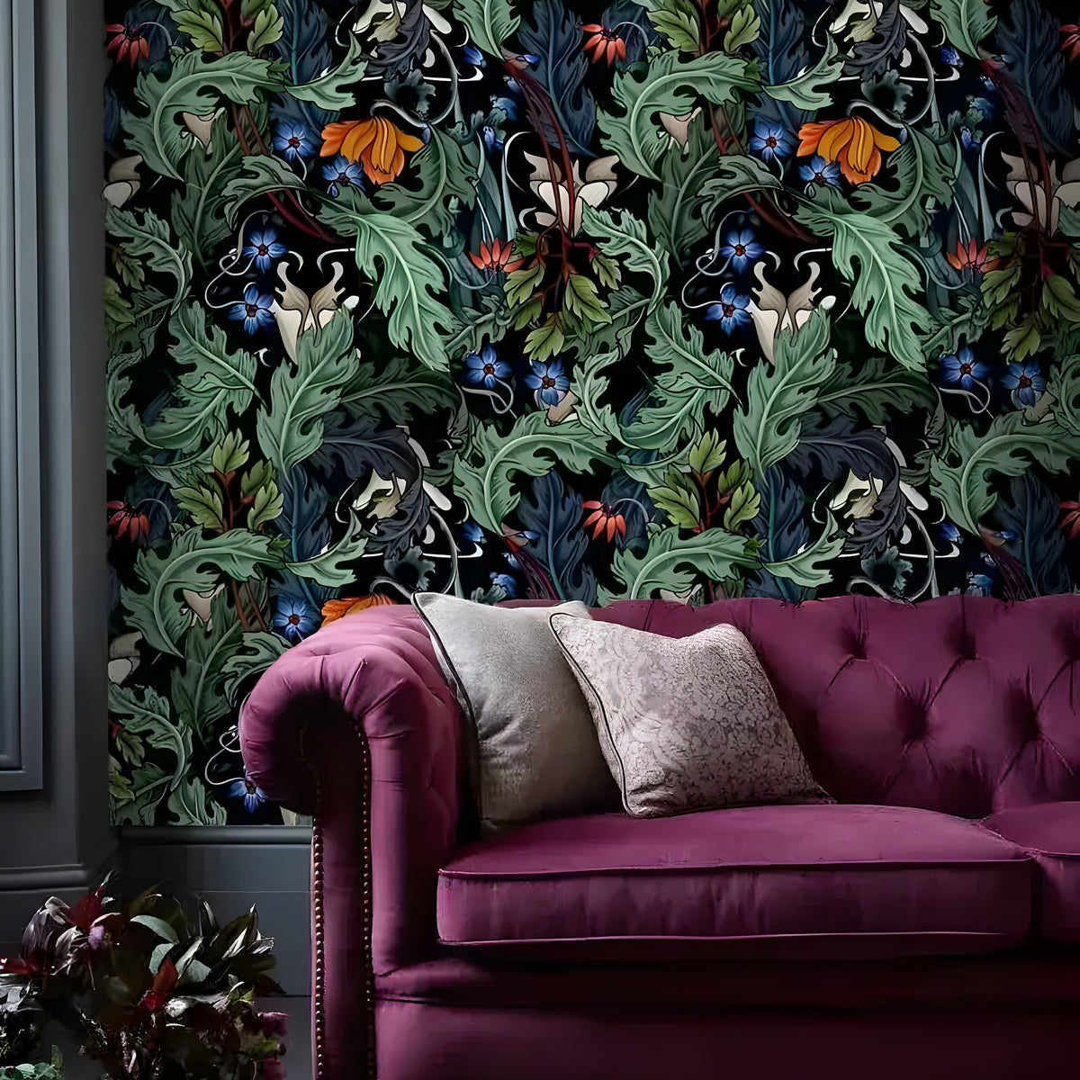 Vintage dark botanical wallpaper with acanthus leaves and skulls in a room with a burgundy velvet tufted sofa