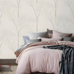 Bedroom setting with delicate flower wallpaper showing gray outline blooms on cream, pink bedding on bed