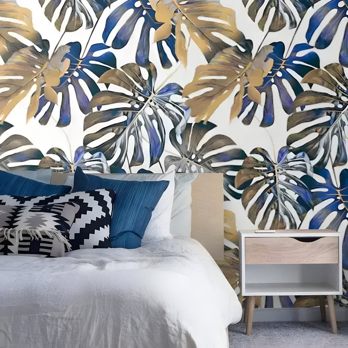 Blue oversized tropical monstera leaf wallpaper in a bright room with natural furnishings