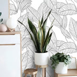 Black and white minimalist linear leaves wallpaper in Scandinavian room, white-wood sideboard with snake plant and sphere decor