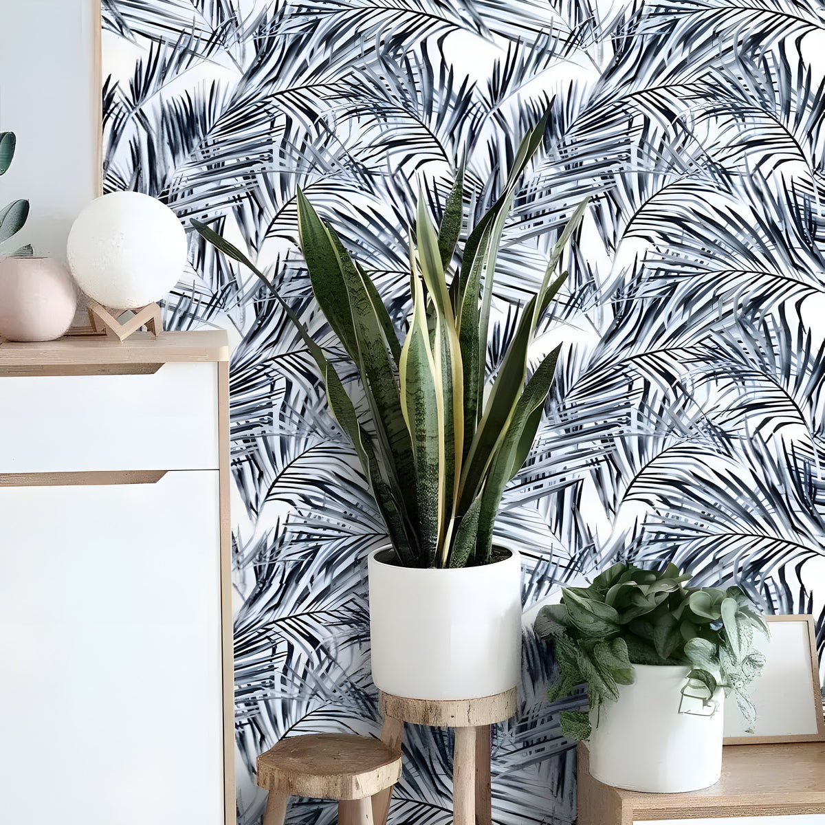 Blue tropical coconut palm leaves wallpaper in entryway with white sideboard, snake plant and wood stool