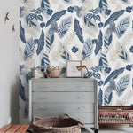 Gray and blue tropical foliage wallpaper installed in a room, muted gray-blue tropical leaves and birds on pale background