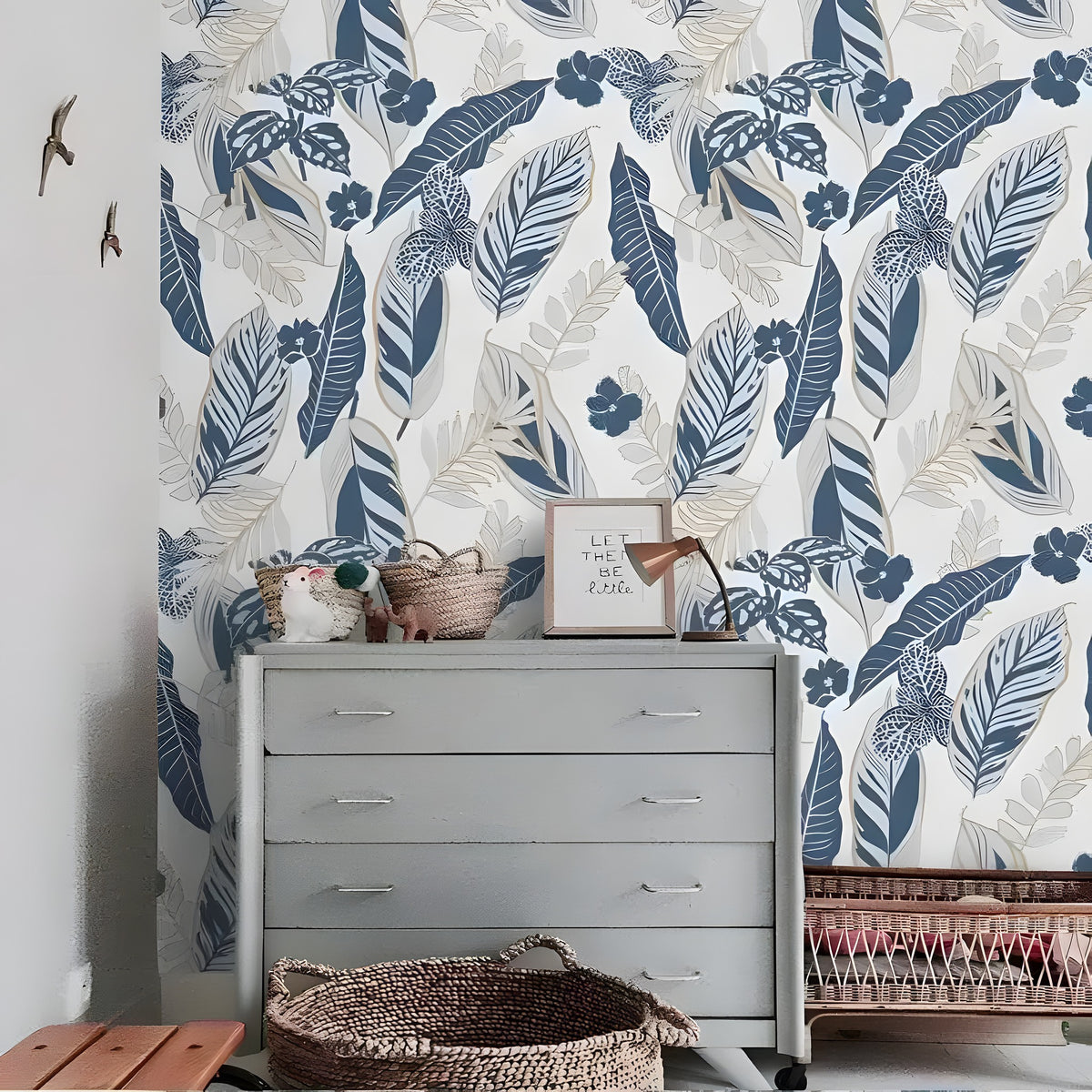 Gray and blue tropical foliage wallpaper installed in a room, muted gray-blue tropical leaves and birds on pale background