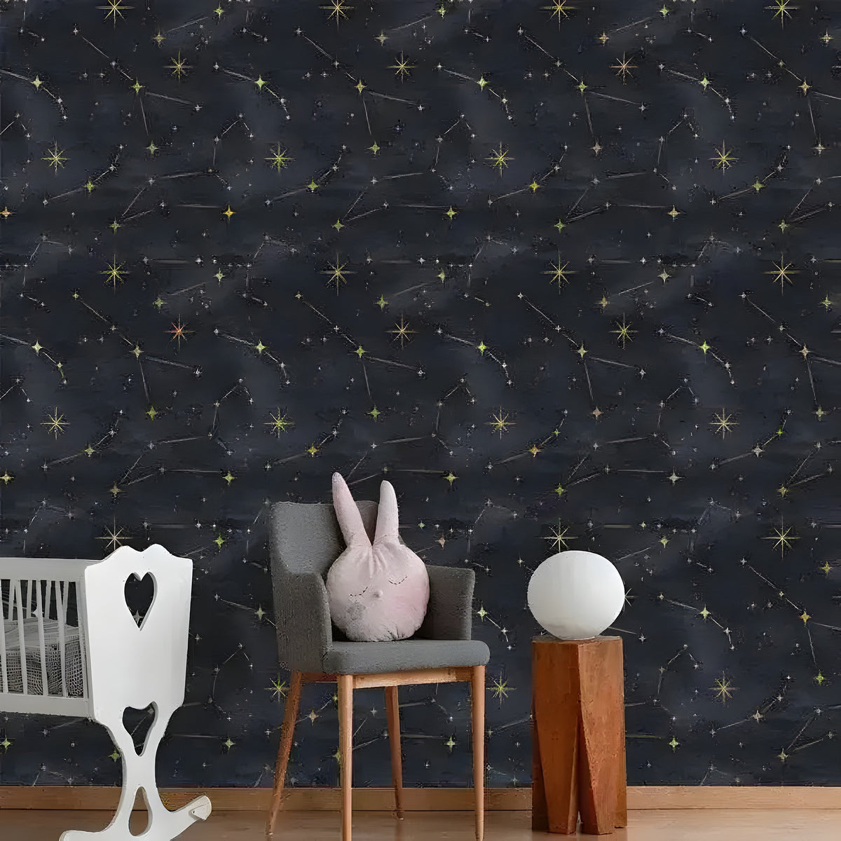 Nursery with white crib and gray chair, dark celestial watercolor wallpaper with gold star constellations
