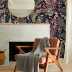 Tropical floral hummingbirds butterflies wallpaper on navy with pink heliconias and parrots as chimney breast behind tan lounge chair