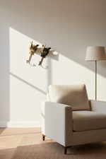 A modern beige armchair in a sunlit room with a floor lamp, woven rug, and two decorative wall-mounted rabbit sculptures on the wall.