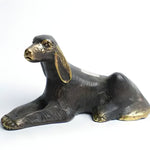 Dark antique brass miniature dog figurine lying with head raised, 3/4 front angle