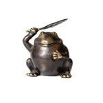 Solid Brass Frog Figurine holding a feather quill aloft, front 3/4 view, dark brass finish, white background