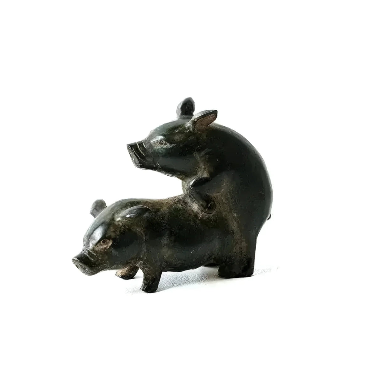 Two pig brass figurines in mating pose, smooth black polish finish, on white background