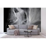 Black and white rhino wall mural installed behind a grey sectional sofa, dramatic close-up of rhino eye and horn