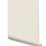 Rolled wallpaper swatch of geometric floral art deco pattern in beige and white repeating starbursts on white
