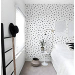 Black and white chevron removable wallpaper in a bright bedroom with white bedding and wooden ladder